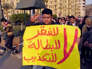 An Egyptian protester carrying a banner saying: No to poverty, No to Unemployment, No to Torture (AFP Photo)