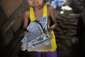 A file picture taken on March 28, 2013 of a boy showing the torn pages of a Koran at his ransacked house after sectarian violence spread through central Myanmar, in Zeegone, Bago division. Two years after a repressive junta ceded power, Myanmar is grappling with a surge in religious extremism that experts trace to anti-Muslim "provocateurs" including radical Buddhist monks. (AFP Photo)