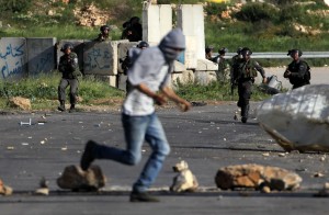 Israeli security forces take position as a Palestinian protester runs for cover during clashes outside Ofer prison near the West Bank city of Ramallah  (AFP Photo)