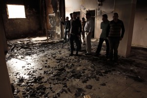 People inspect the inside of a the destroyed room in a building that was burnt down during a night of sectarian clashes between Christians and Muslims in Al-Khasous on 6 April (AFP Photo)