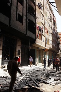 People walk through debris outside a building that was burnt down during sectarian clashes between Christians and Muslims in Al-Khusus, a poor area in Qalyubia governorate, north of Cairo on April 6, 2013 (AFP File Photo)