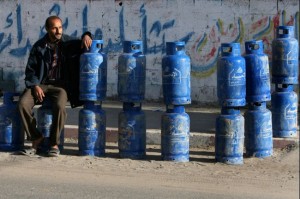 A Palestinian seller sits with cooking gas cylinders smuggled into the Gaza Strip from Egypt through a tunnel. On Monday, the government set new prices for butane gas cylinders, with the price of 12.5kg cylinders rising to EGP 8 per cylinder and the price of 25kg cylinders rising to EGP 16, a rise of 60% for both sizes of cylinder (Mahmud Hams/ AFP Photo/Getty Images) 