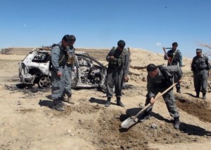 An Afghan policeman digs alongside a destroyed car after a NATO helicopter strike near Ghazni on March 30, 2013 (AFP/File) 
