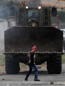 A Palestinian throws a petrol bomb towards a digger of the Israeli army during clashes between Palestinians and Israelis soldiers at the gate of the Ofer prison after a march marking the 65th Nakba day or "Day of Catastrophe" in the West Bank city of Ramallah   (FP Photo / Abbas Momani) 