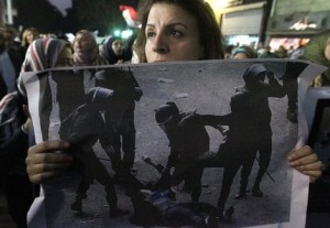 An Egyptian woman holding the widespread picture of a woman who was stripped and beaten by military police during clashes as Egyptians gather for a protest, Cairo December 20, 2011 (AFP File Photo)